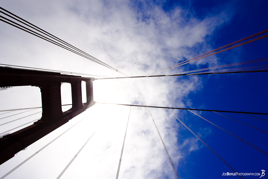A photo of one of the Golden Gate Bridge towers and cables against the sky. 