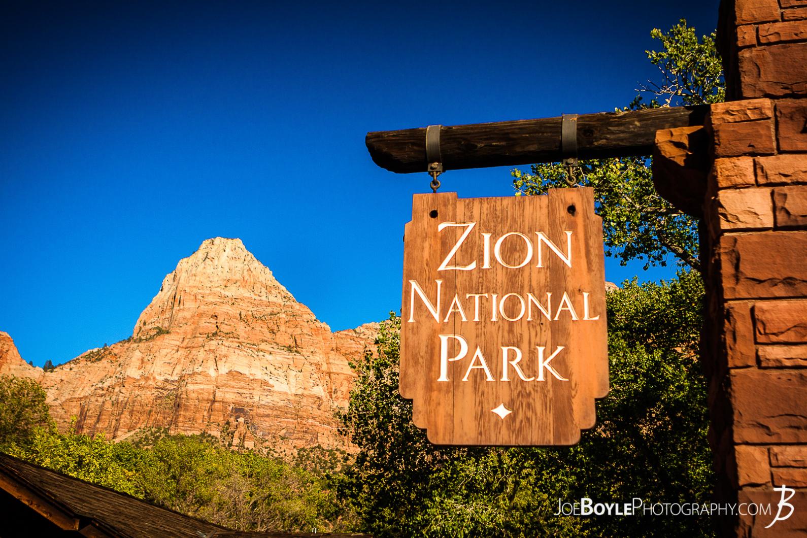 Here is a photo of the sign at the entrance of Zion National Park with a canyon in the background and a beautiful blue sky!